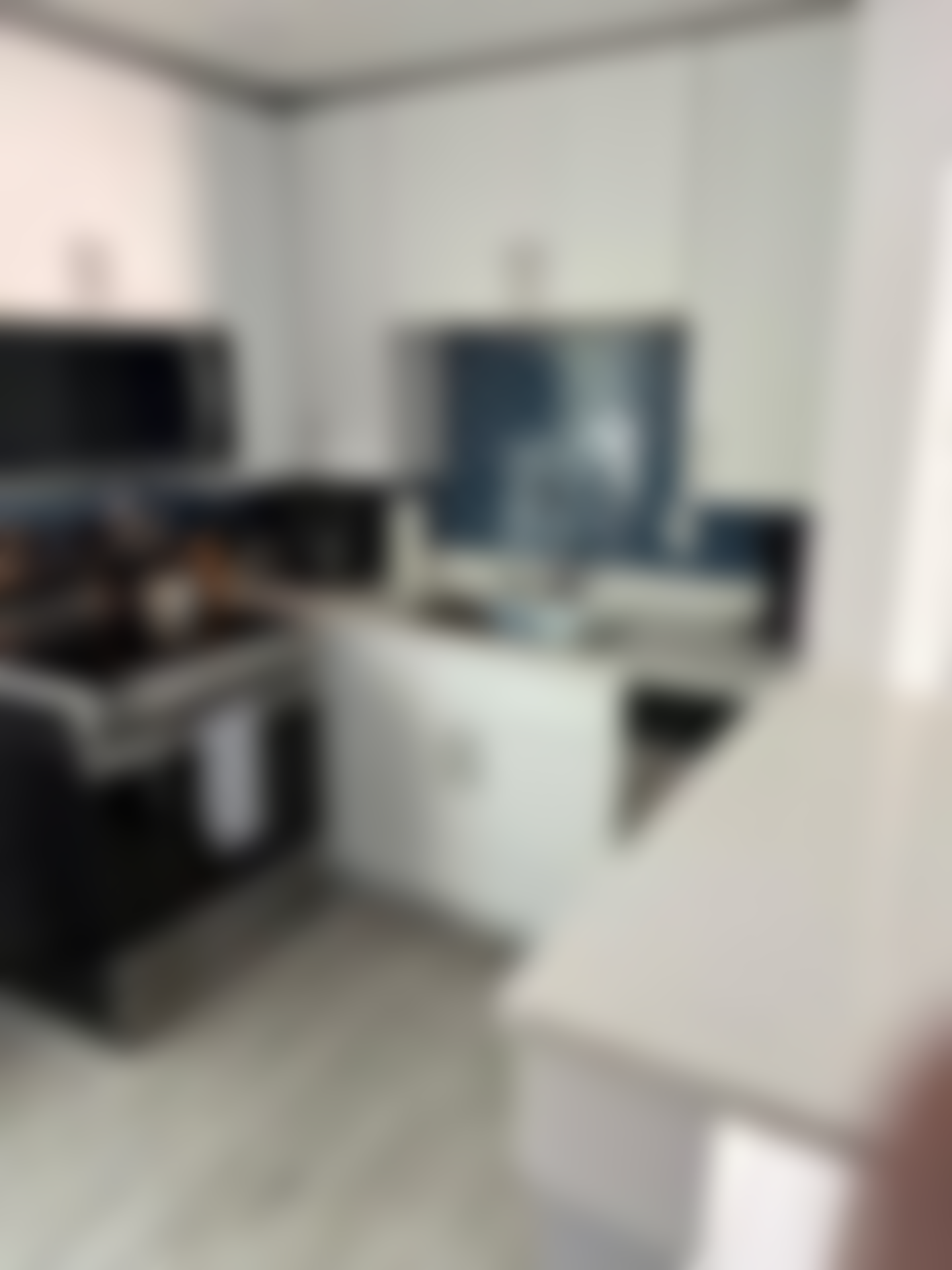 A blurry picture of a kitchen with white cabinets and black appliances.