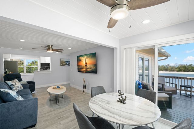 A living room with a couch , table , chairs and a ceiling fan.