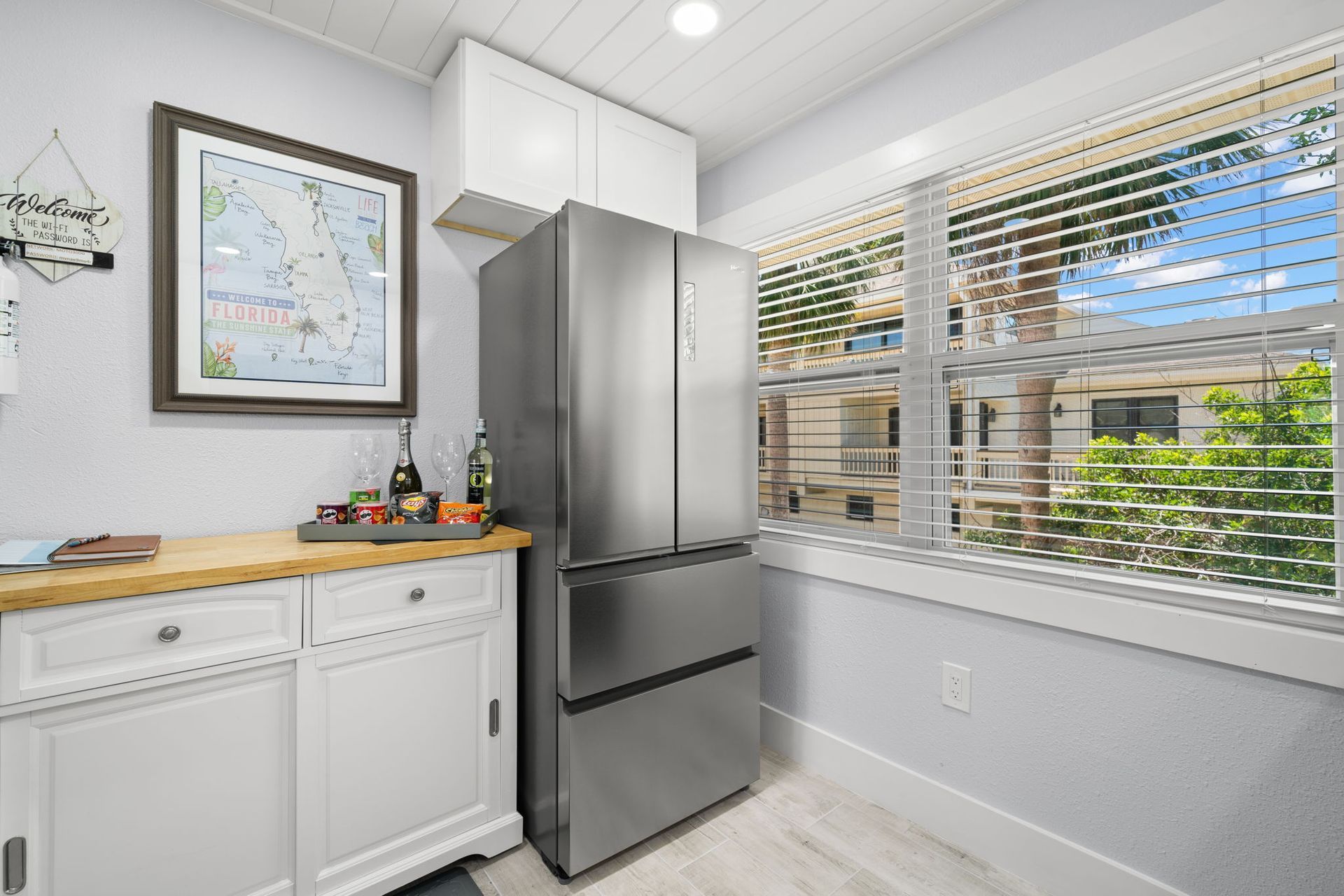 A kitchen with a stainless steel refrigerator and a large window.