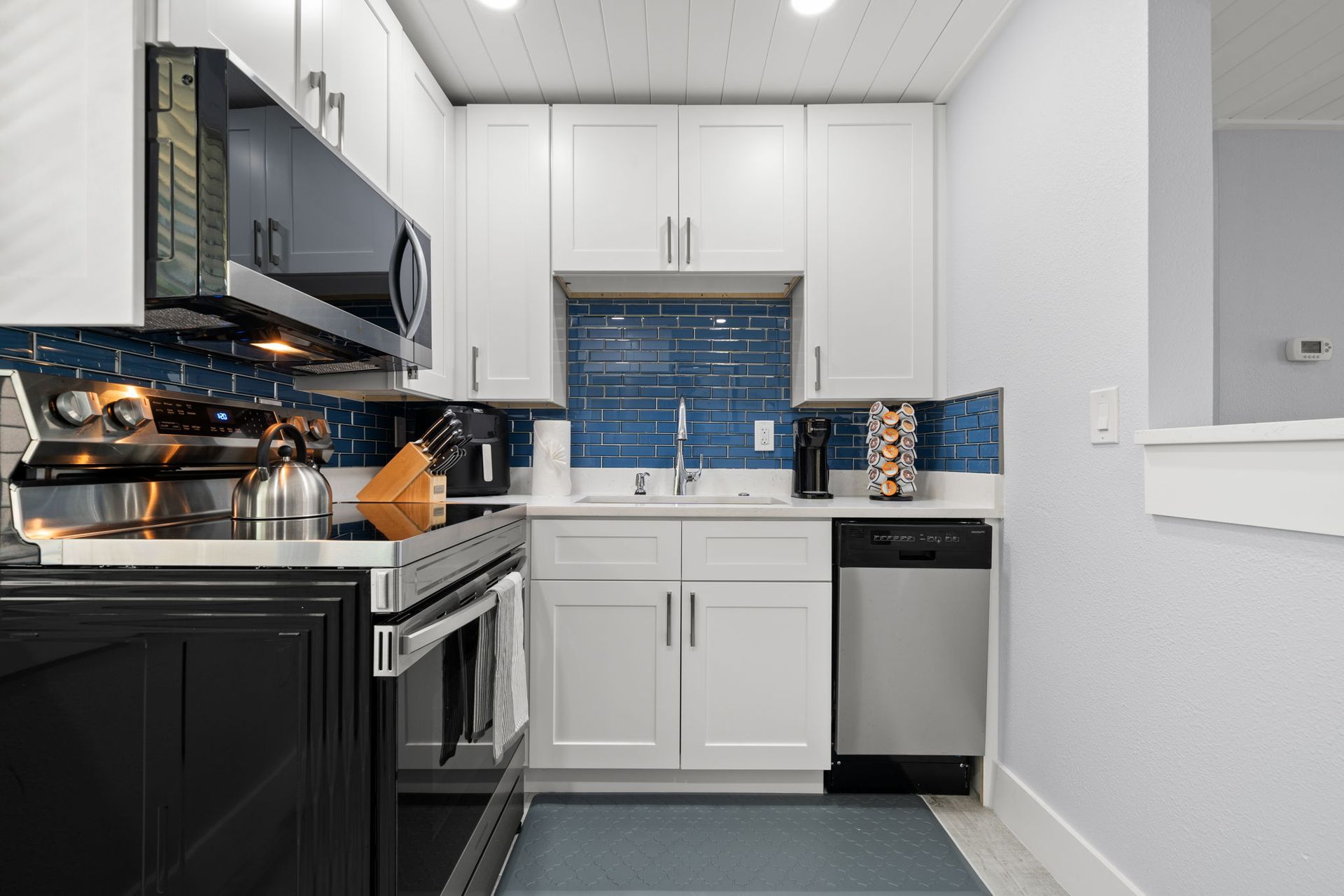 A kitchen with white cabinets , stainless steel appliances , a stove and a dishwasher.