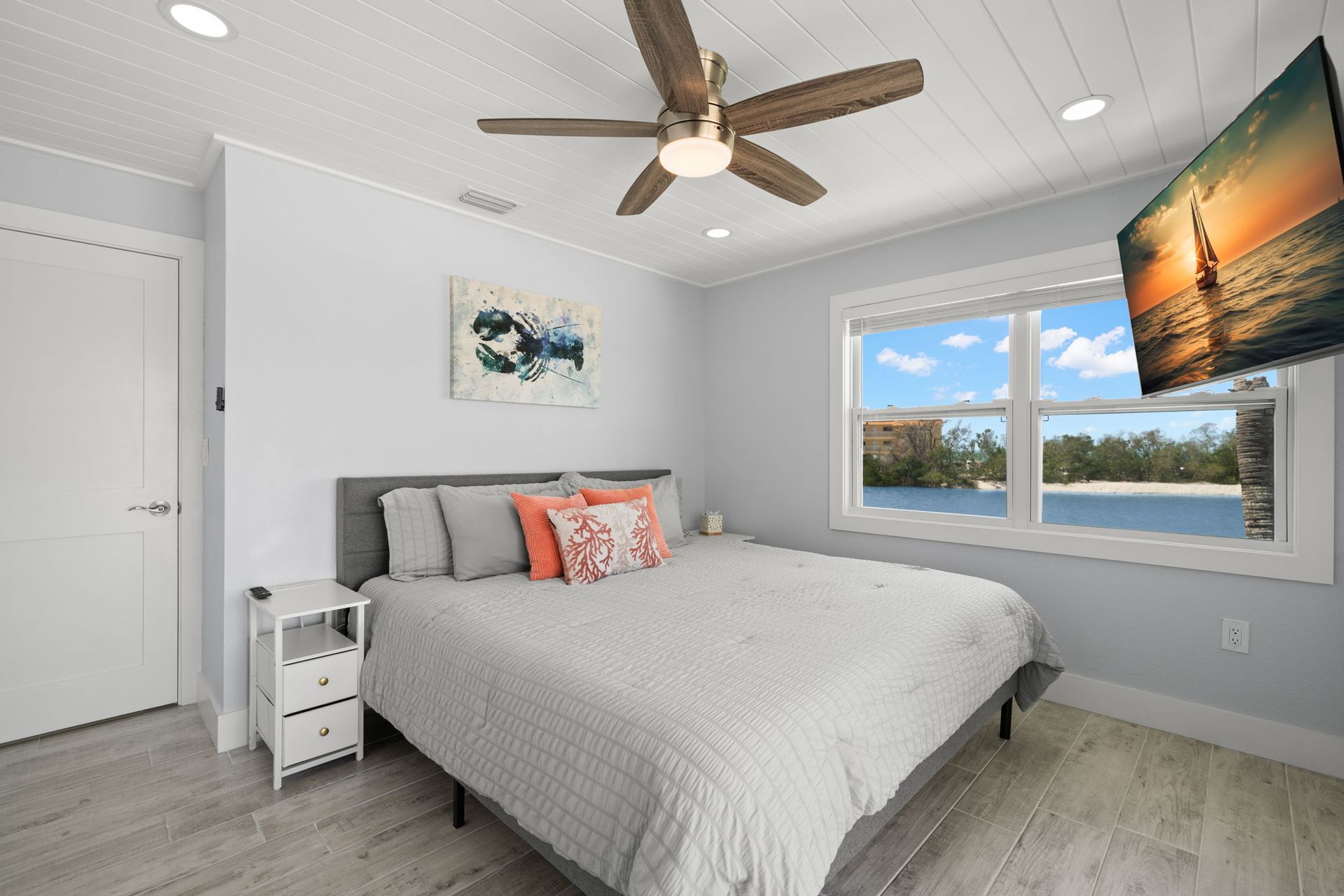 A bedroom with a king size bed , ceiling fan and television.