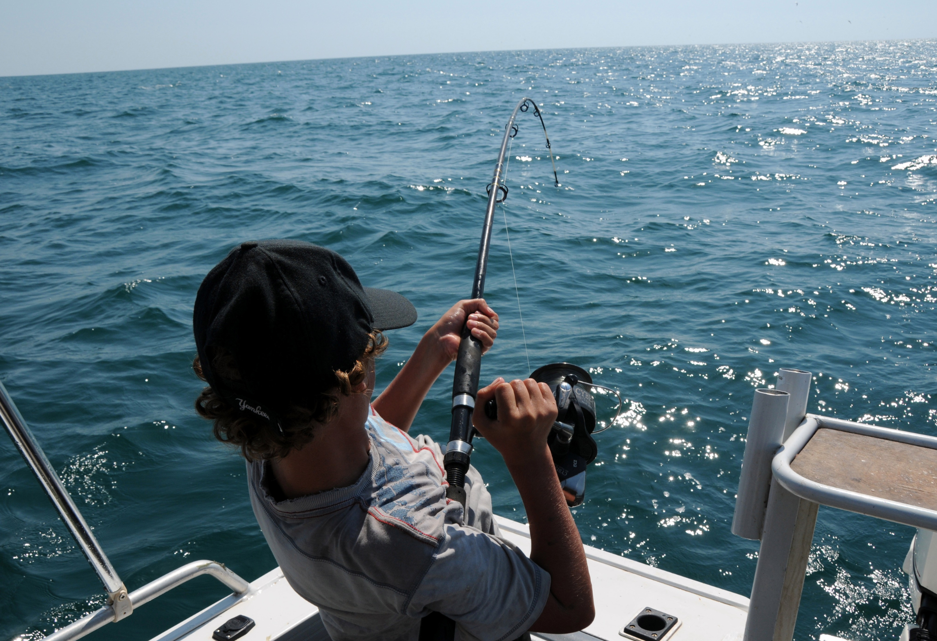 A man is fishing on a boat in the ocean.