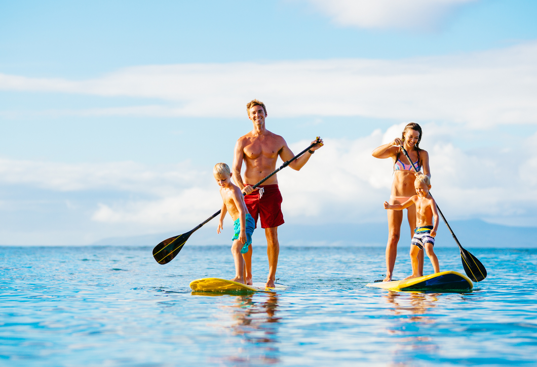 A family is standing on paddle boards in the ocean.