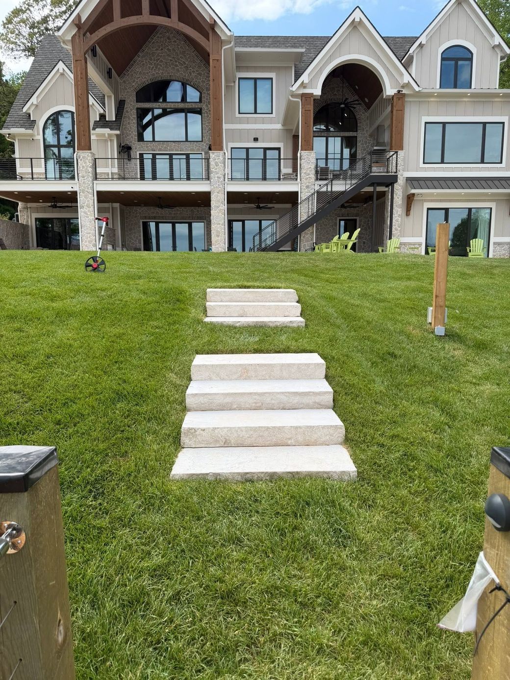 Stone steps up a grassy slope to a large stone townhouse with arched entrances.