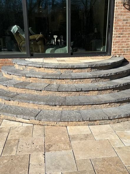 Curved stone steps leading to a glass doorway beside a brick wall