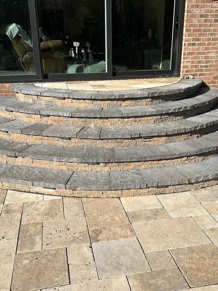 Curved stone steps leading to a glass storefront entrance with tiled pavement below