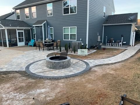 Backyard patio with fire pit, stone path, outdoor chairs, and a gray two-story house
