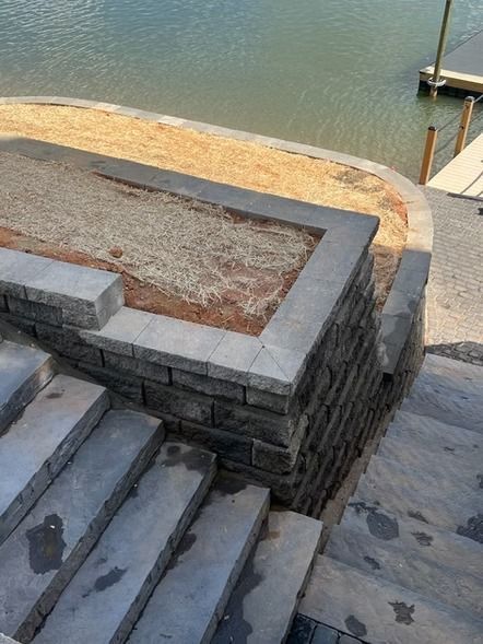 Stone steps beside a waterfront terrace with a dock and calm water in the background