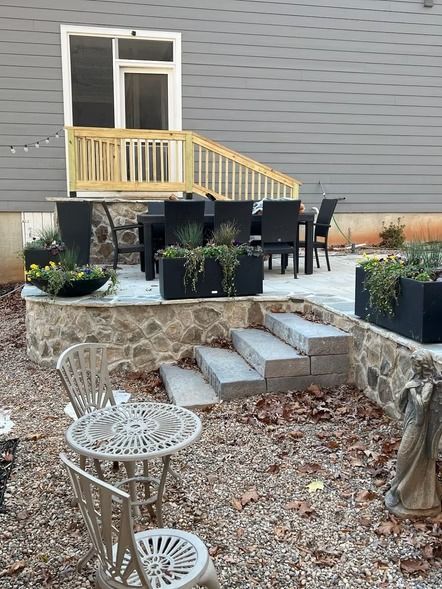 Backyard patio with stone steps, round seating area, balcony, and outdoor furniture.