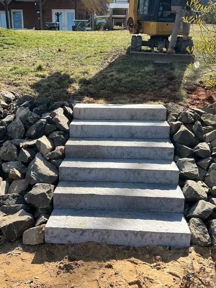 Concrete steps built into a rocky hillside leading up to a yard near a house