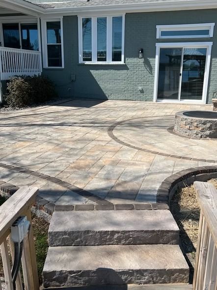 Stone patio with curved steps leading to a house’s back entrance and sliding glass door