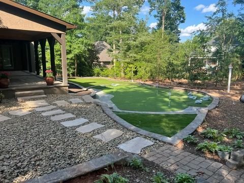 Backyard patio with stepping-stone path, gravel, and a landscaped lawn bordered by trees and shrubs.