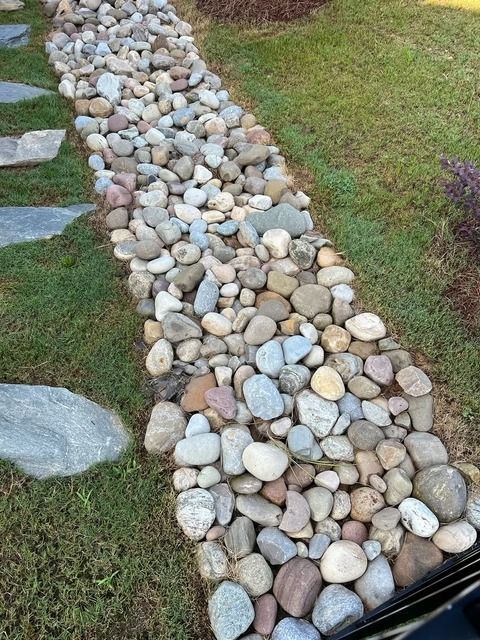 Rock-lined garden path bordered by grass and stepping stones
