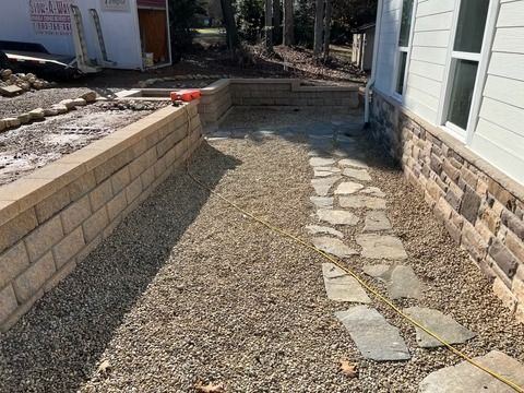 Gravel walkway beside a house with stone edging and a stepping-stone path