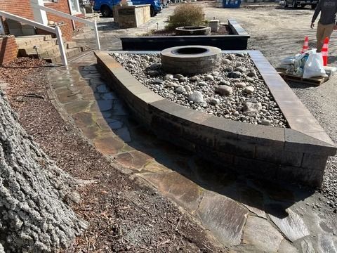 Curved stone garden wall with gravel fill and a circular planter under construction outdoors