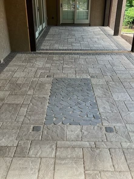 Stone-paved walkway leading to a building entrance with a central gray cobblestone strip