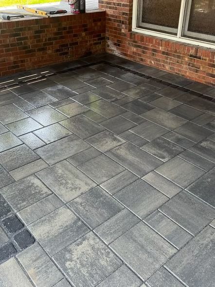 Empty gray paver patio beside a brick house wall and window