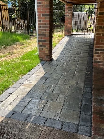 Covered brick patio with gray pavers and grassy yard beside it