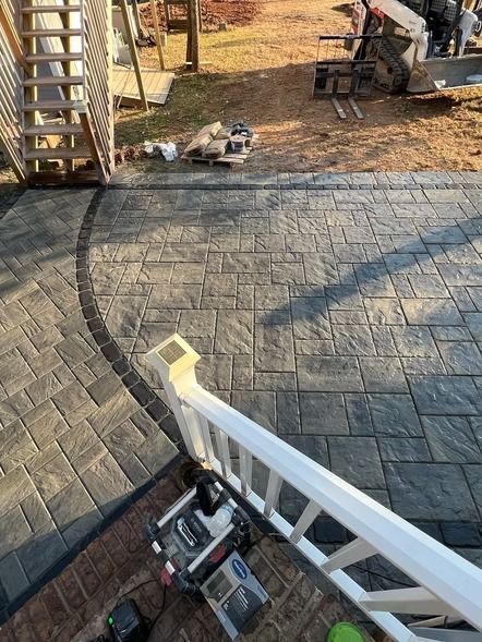 Construction tools on a gray paver patio beside a white ladder in a backyard setting