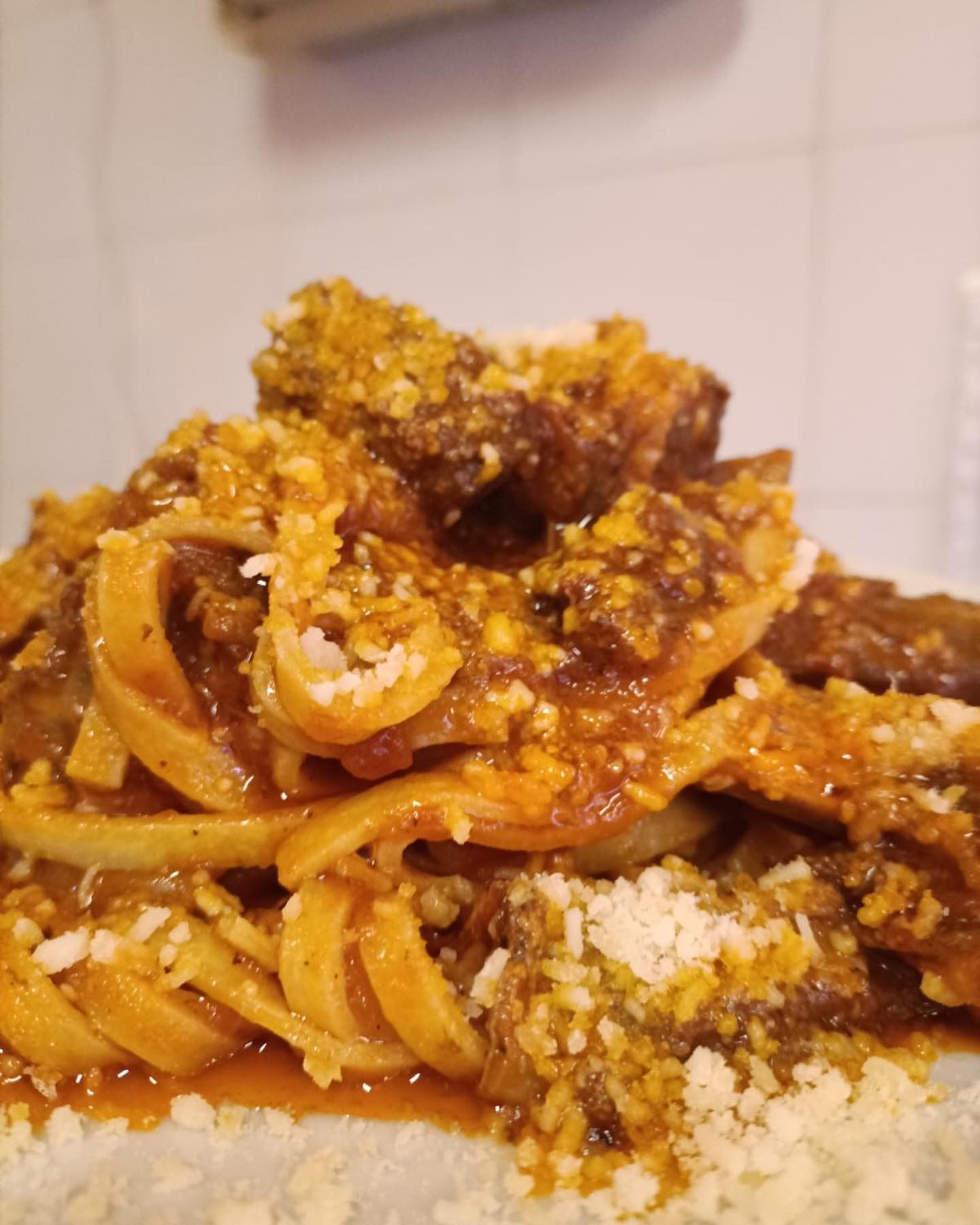 Primo piano di pasta al ragù di pomodoro e formaggio grattugiato su un piatto