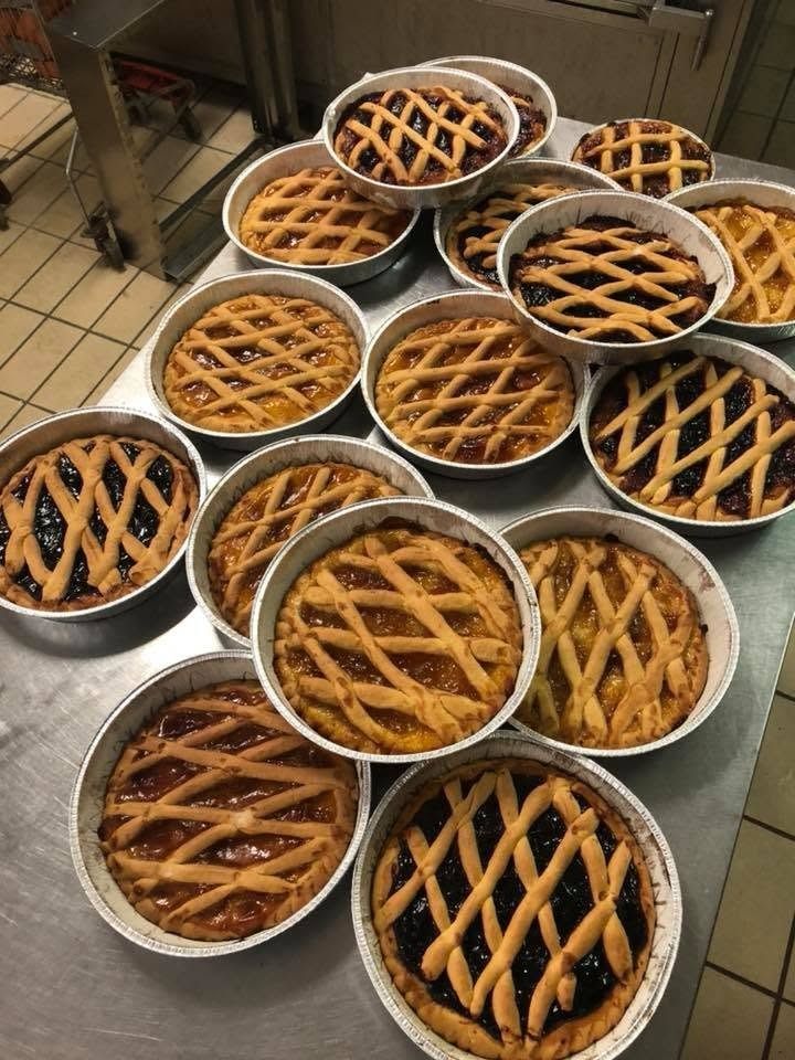 Diverse torte a grata cotte al forno in teglie di metallo, disposte su un bancone della cucina.