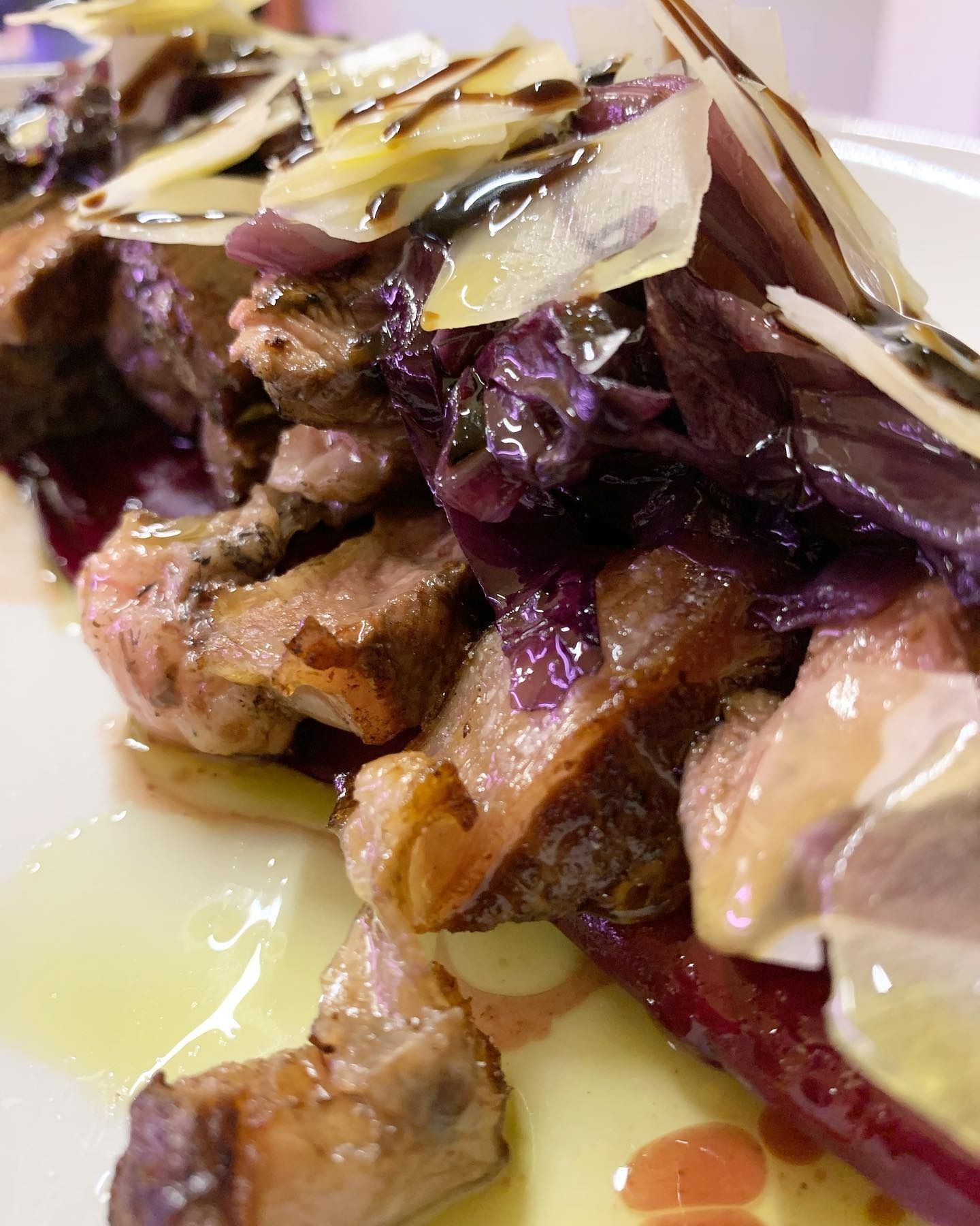 Brasato di manzo con cavolo viola e formaggio grattugiato su un piatto bianco, condito con salsa.