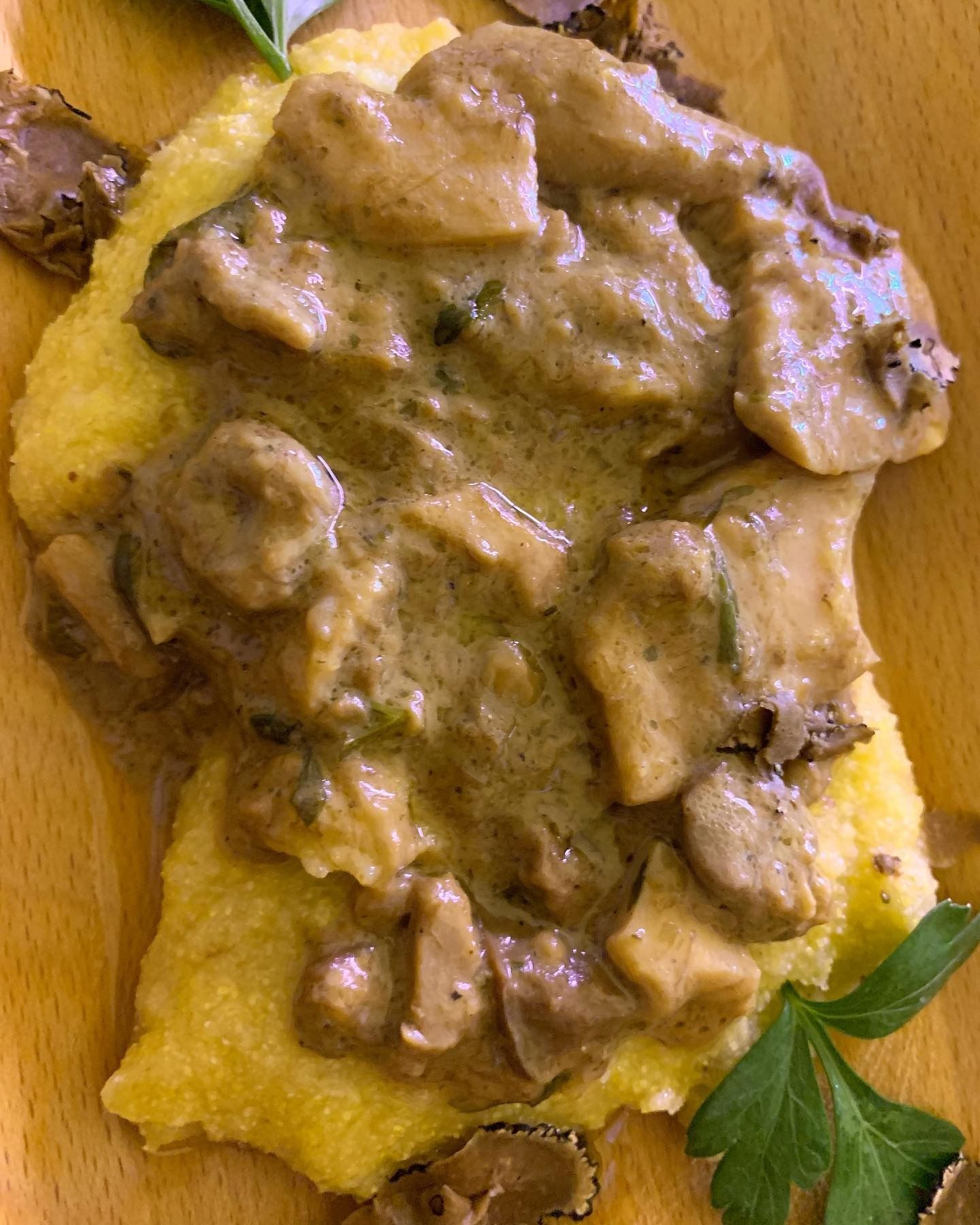 Pasta condita con cremosa salsa ai funghi, guarnita con prezzemolo e servita su un tagliere di legno.