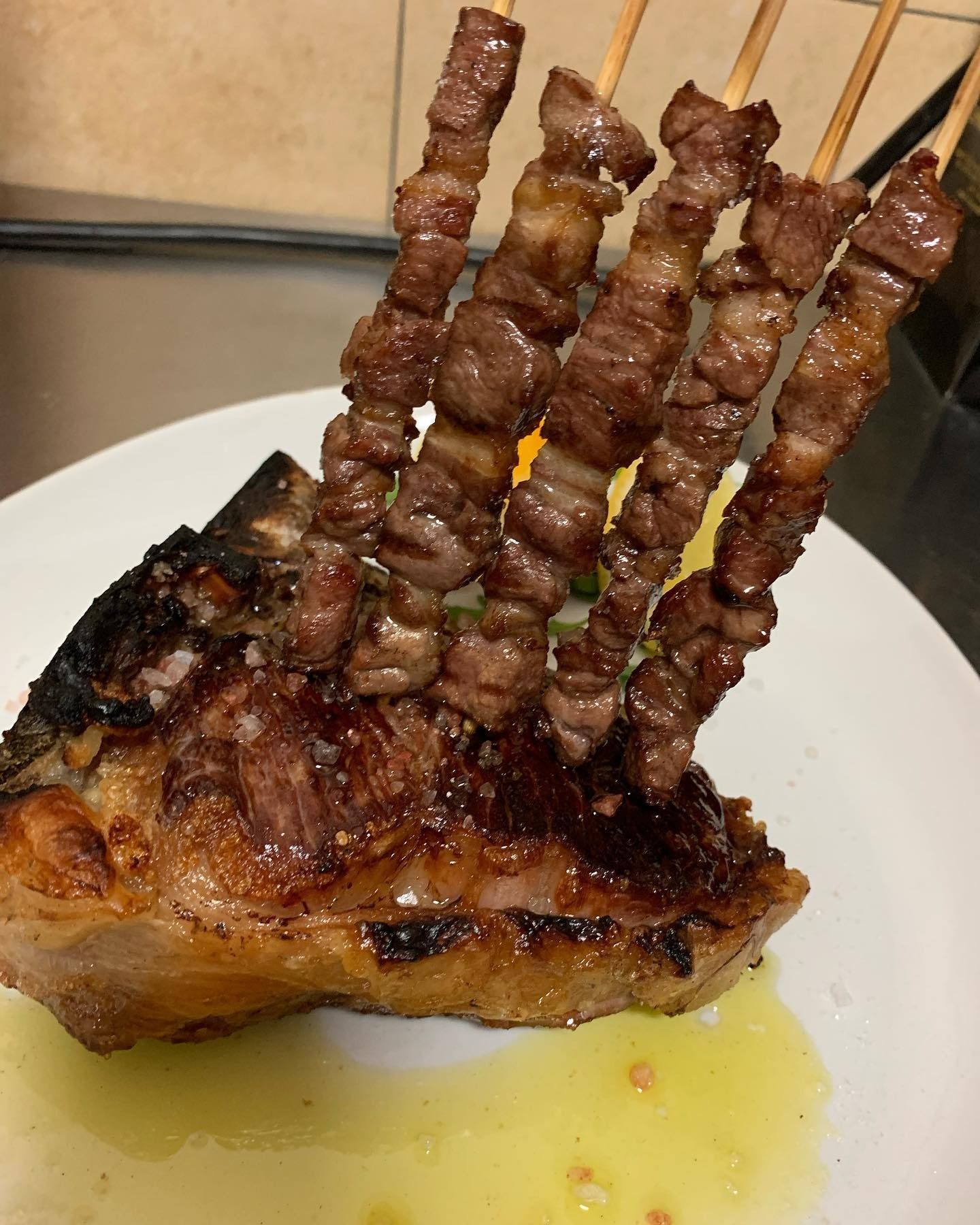 Carne grigliata e spiedini di manzo su un piatto bianco con salsa gialla