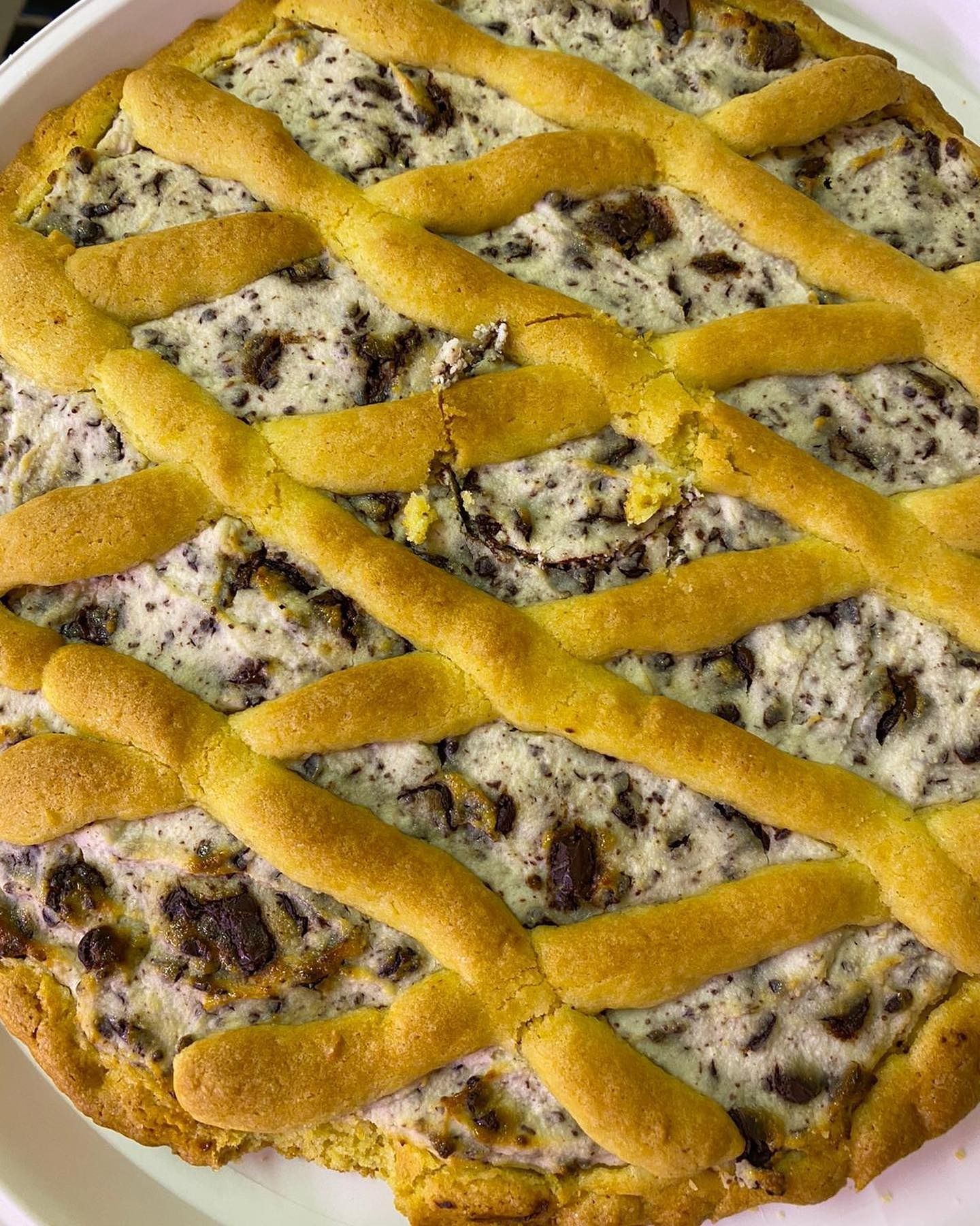 Torta rotonda con copertura a griglia, crosta dorata e ripieno bianco maculato.