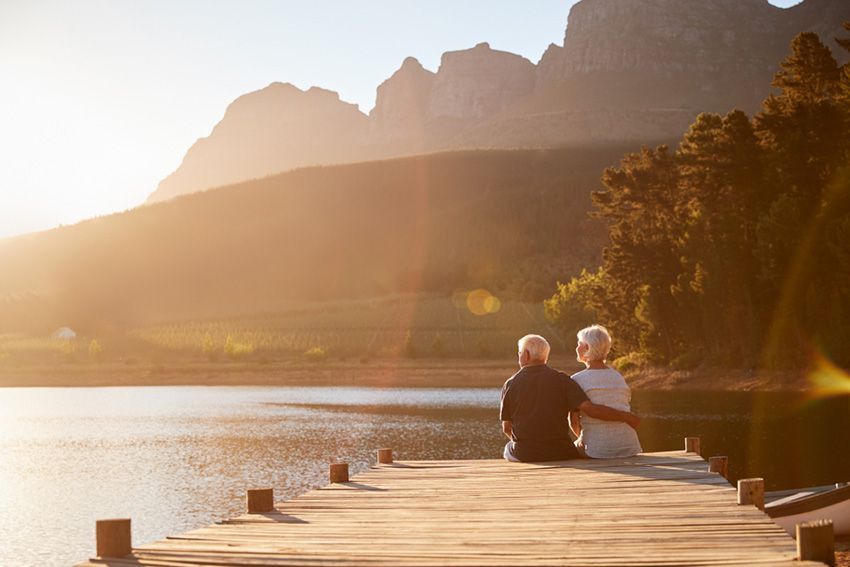 A Man and a Woman Are Sitting on a Dock Overlooking a Lake — Budd & Piper Solicitors & Conveyancers in Tweed Heads, NSW