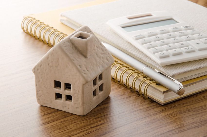 A Small House on Top of a Notebook Next to a Calculator — Budd & Piper Solicitors & Conveyancers in Tweed Heads, NSW