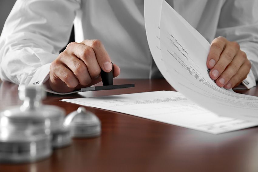 A Man is Stamping a Piece of Paper on a Table — Budd & Piper Solicitors & Conveyancers in Tweed Heads, NSW