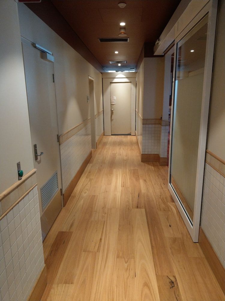 A Long Hallway With Wooden Floors and White Walls — Shields Painting & Decorating in Narrandera, NSW