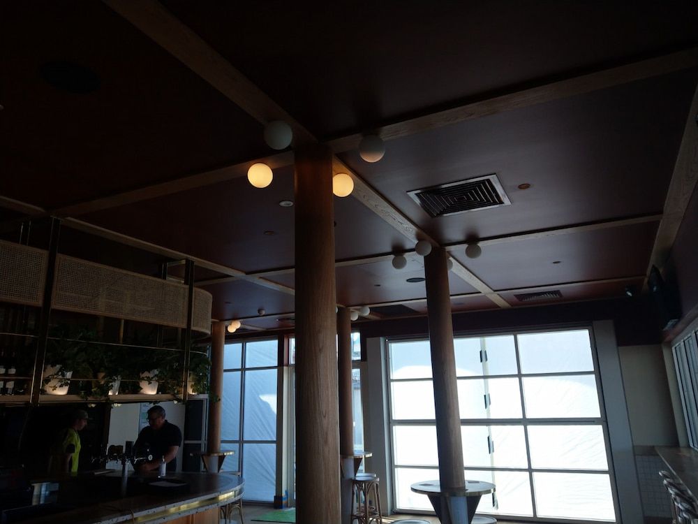 A Man Stands Behind a Bar in a Dark Room — Shields Painting & Decorating in Tumut, NSW