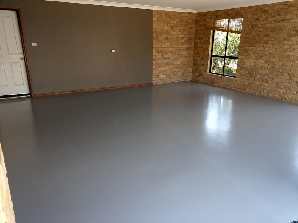 A Large Empty Room With a Concrete Floor and Brick Walls — Shields Painting & Decorating in Tumut, NSW