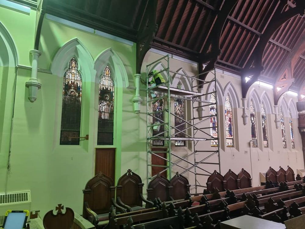 A Man is Standing on a Scaffolding in a Church — Shields Painting & Decorating in Wagga Wagga, NSW