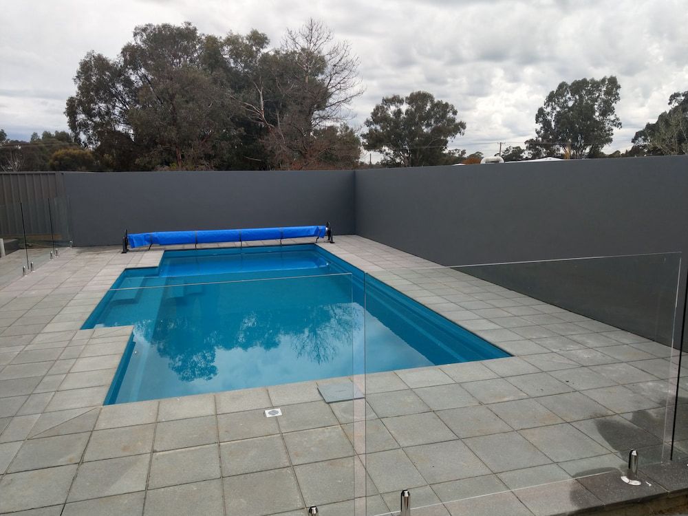 A Large Swimming Pool With a Blue Cover on Top of It — Shields Painting & Decorating in Gundagai, NSW