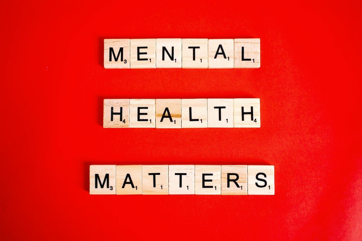 Scrabble tiles spelling “MENTAL HEALTH MATTERS” on a bright red background