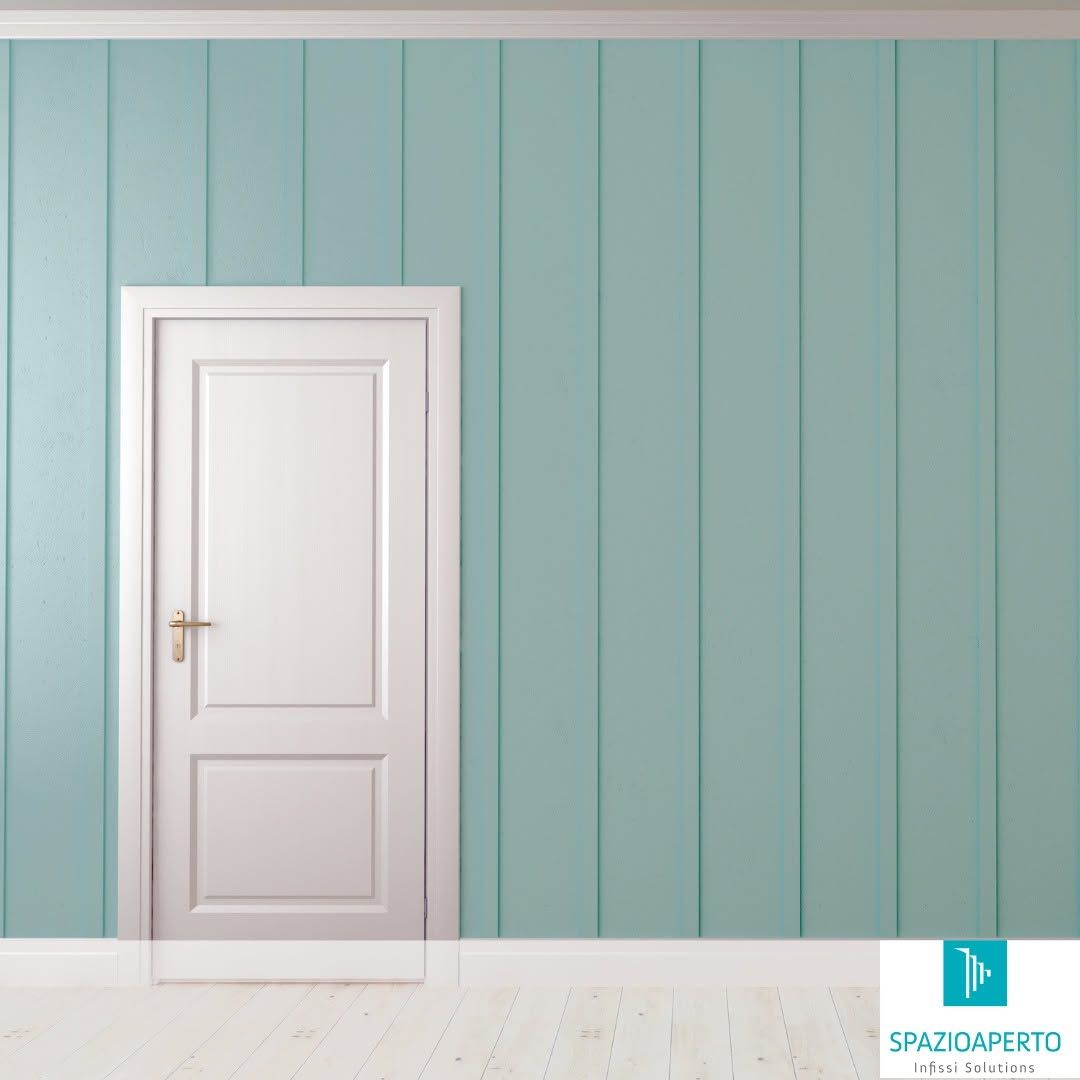 Una porta bianca su una parete rivestita di pannelli color verde acqua pallido, in una stanza minimalista con pavimento in legno bianco.
