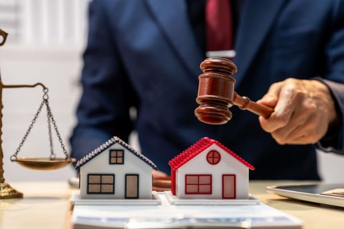 Judge’s gavel over model houses and scales, symbolizing a real estate dispute