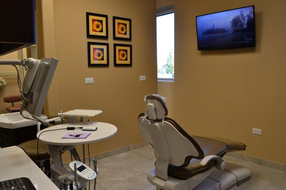 A dental office with a dental chair and a television on the wall.