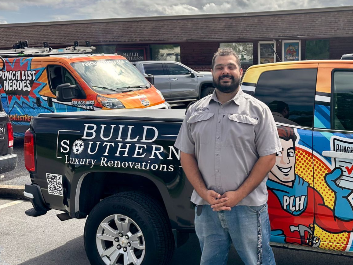 A young man is standing in front of a colorful van. A young man is standing in front of a colorful van.