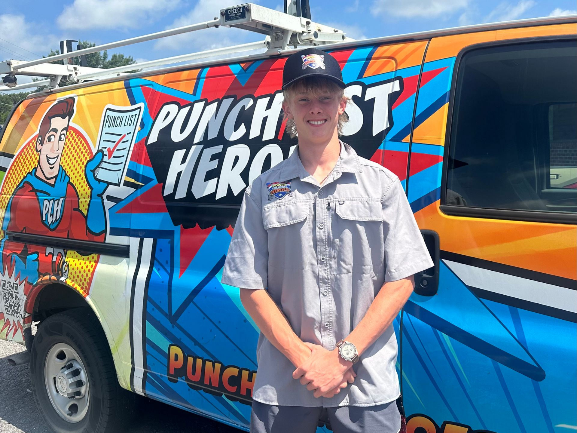 A young man wearing a hat and glasses is standing in front of an orange van. A young man wearing a hat and glasses is standing in front of an orange van.