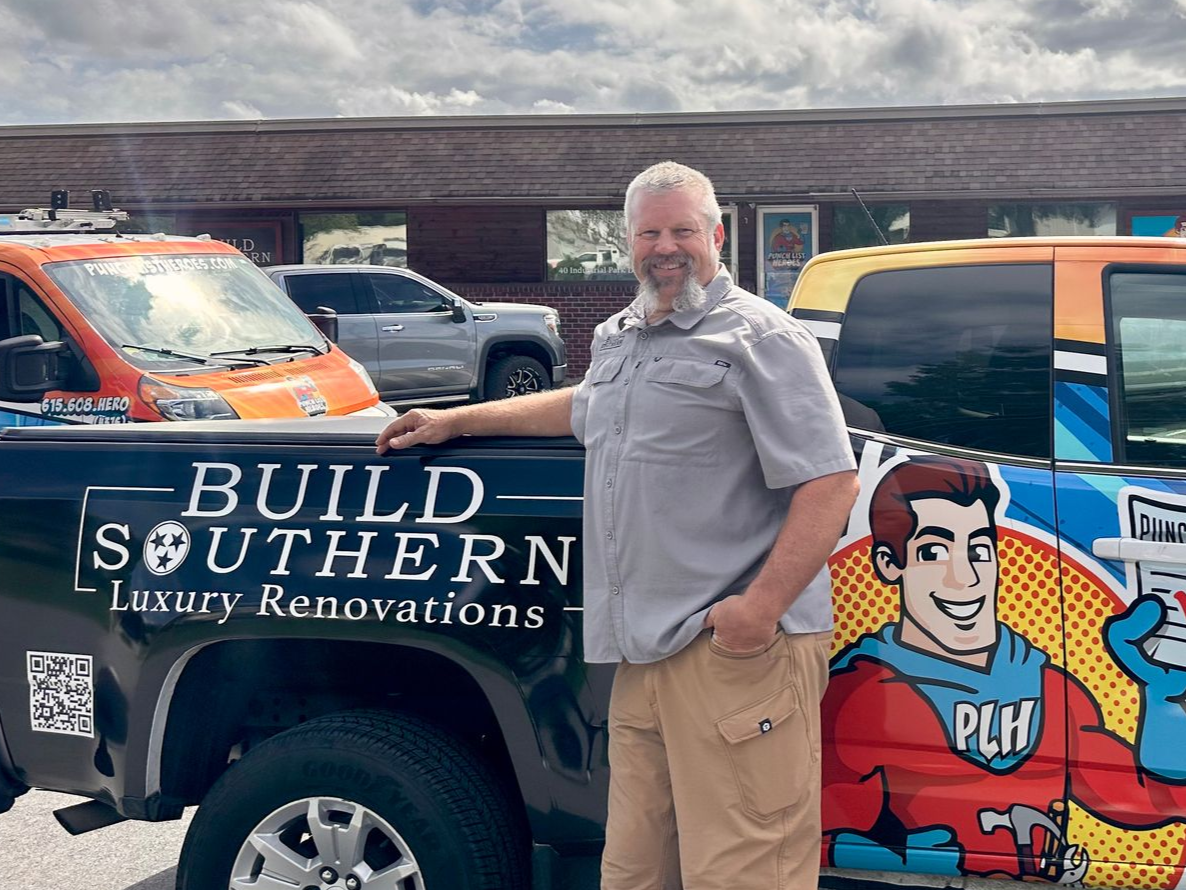 A young man is standing in front of a colorful van. A young man is standing in front of a colorful van.
