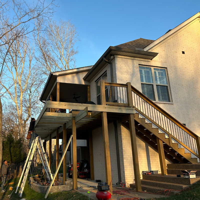 A man is washing the roof of a house and a man is washing the driveway of a house. A man is washing the roof of a house and a man is washing the driveway of a house.