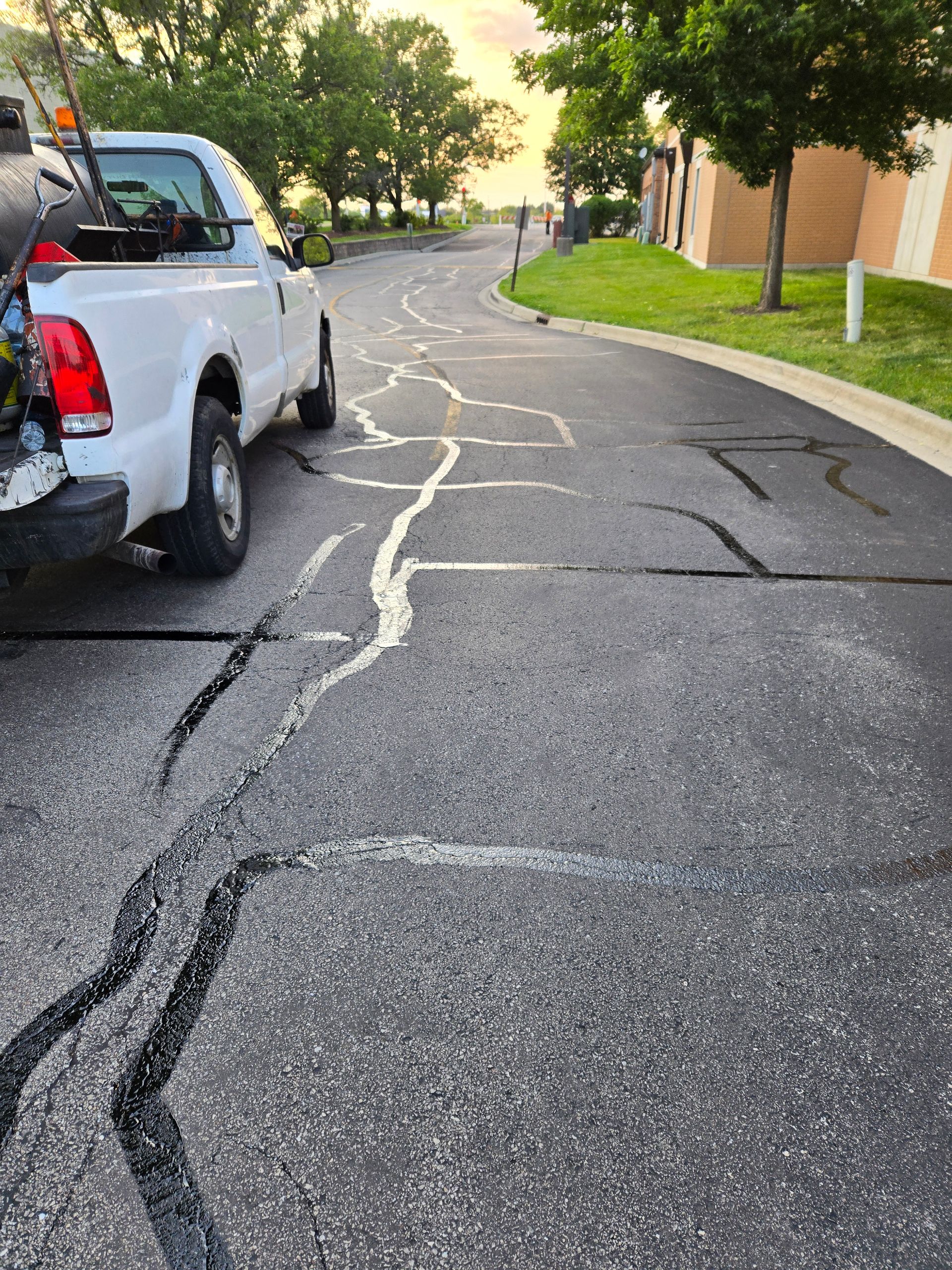 Cracked asphalt street in a suburban neighborhood with houses and trees in the background