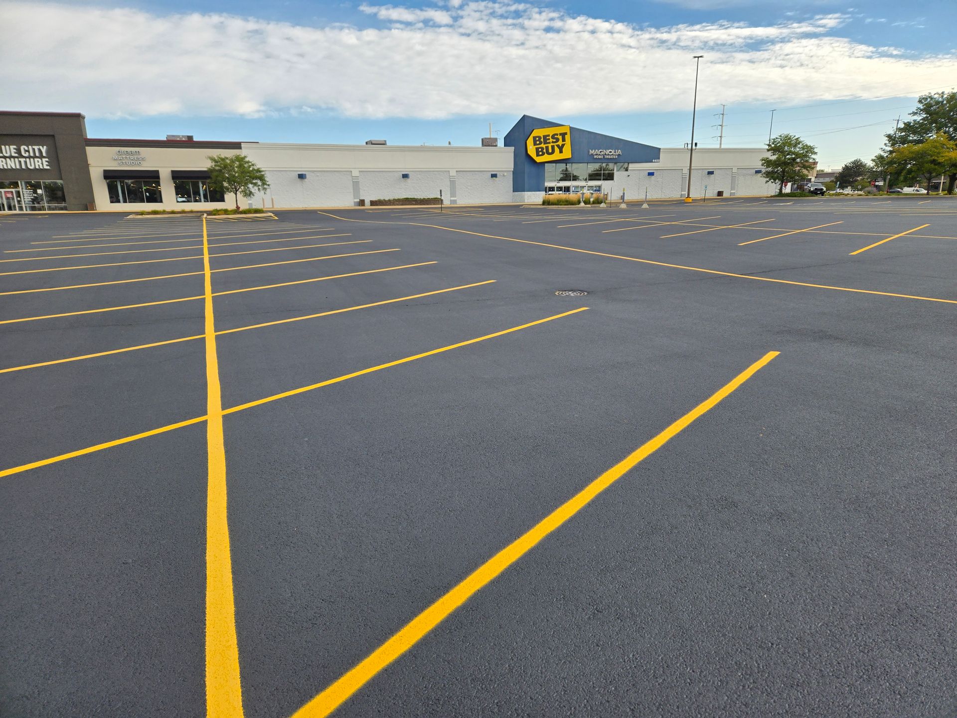 Empty parking lot at dusk with yellow painted pavement markings and a building on the left