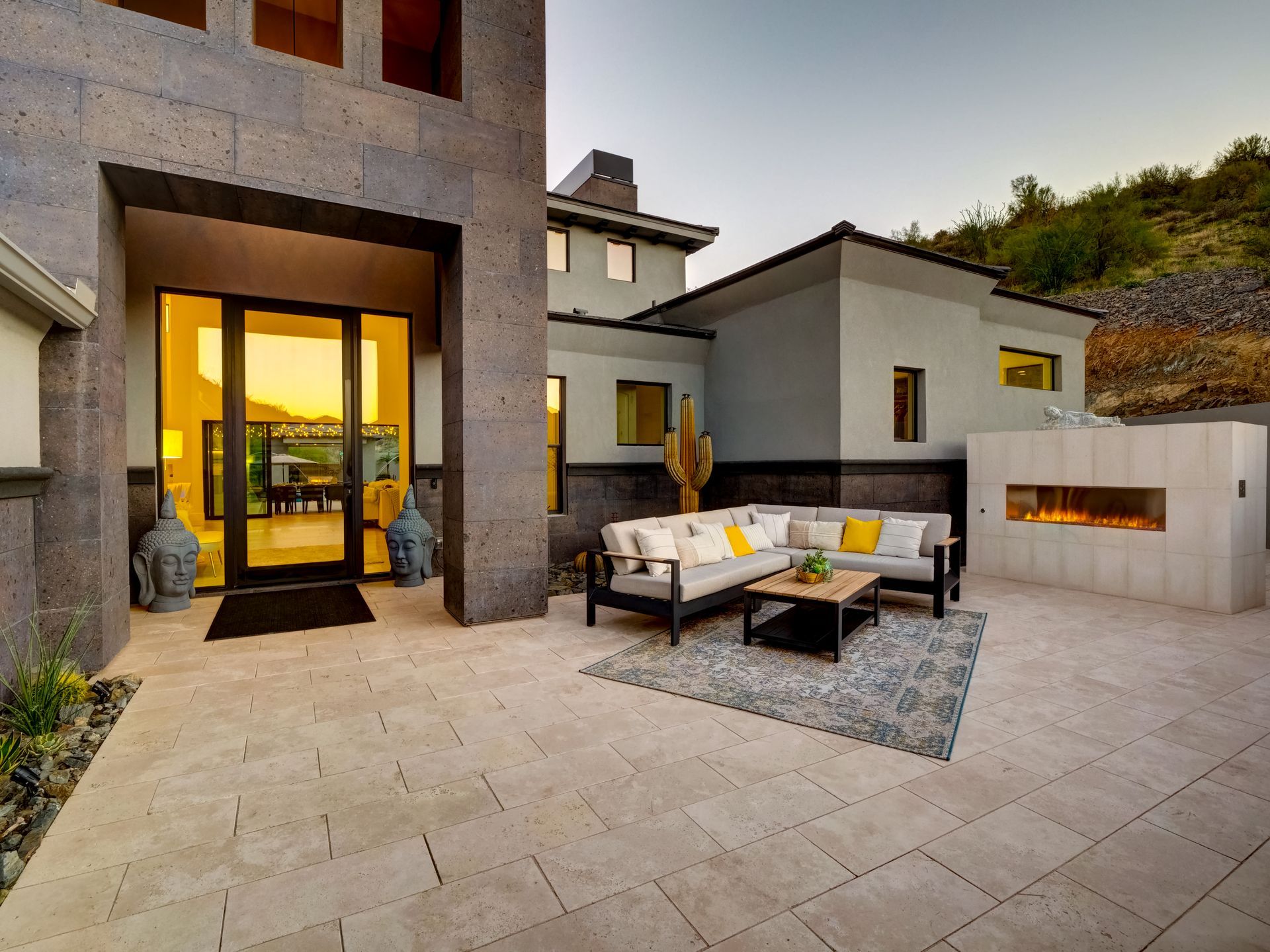 Modern home exterior with outdoor seating and a fireplace.