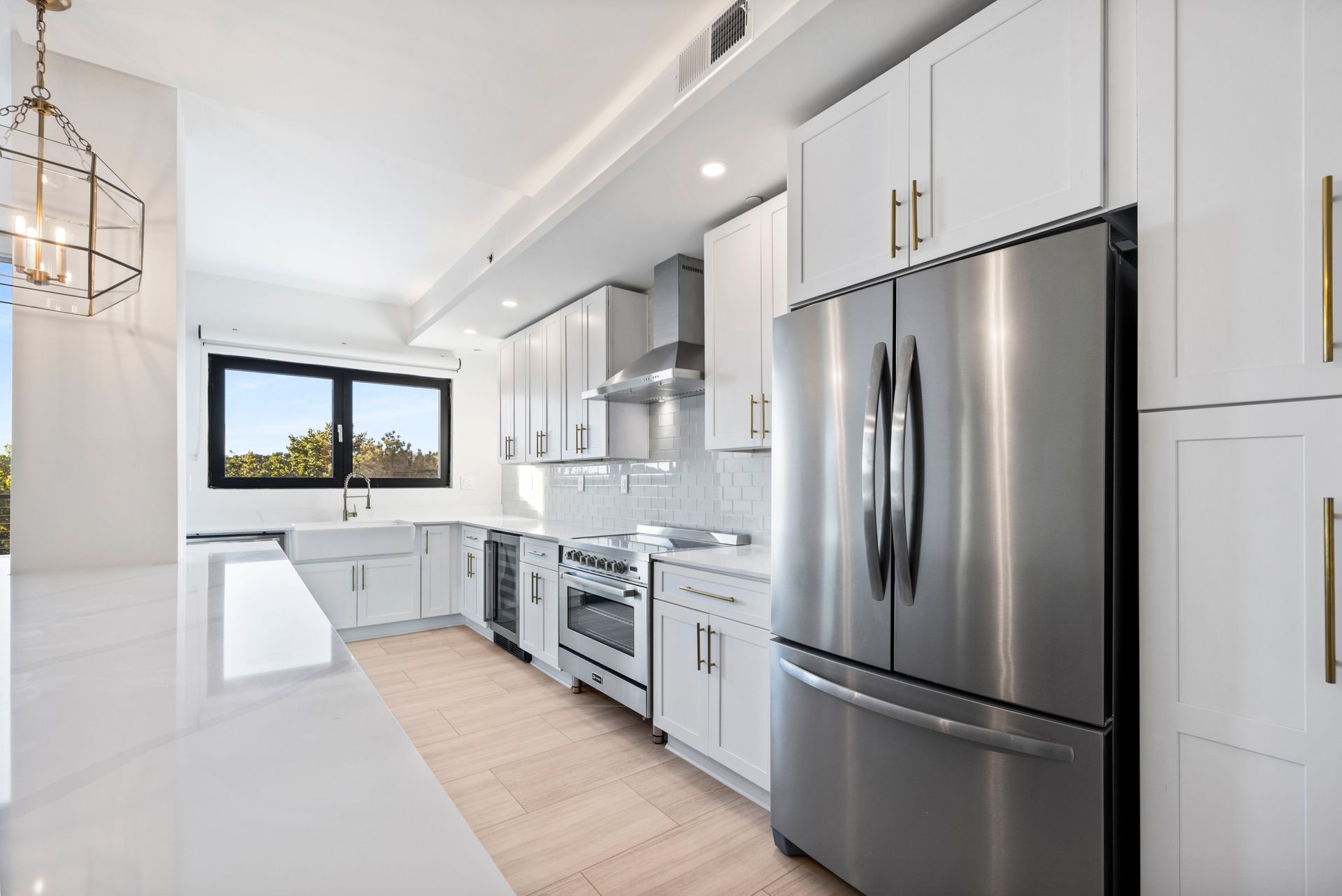 Modern kitchen with white cabinets, stainless steel appliances, and a window.