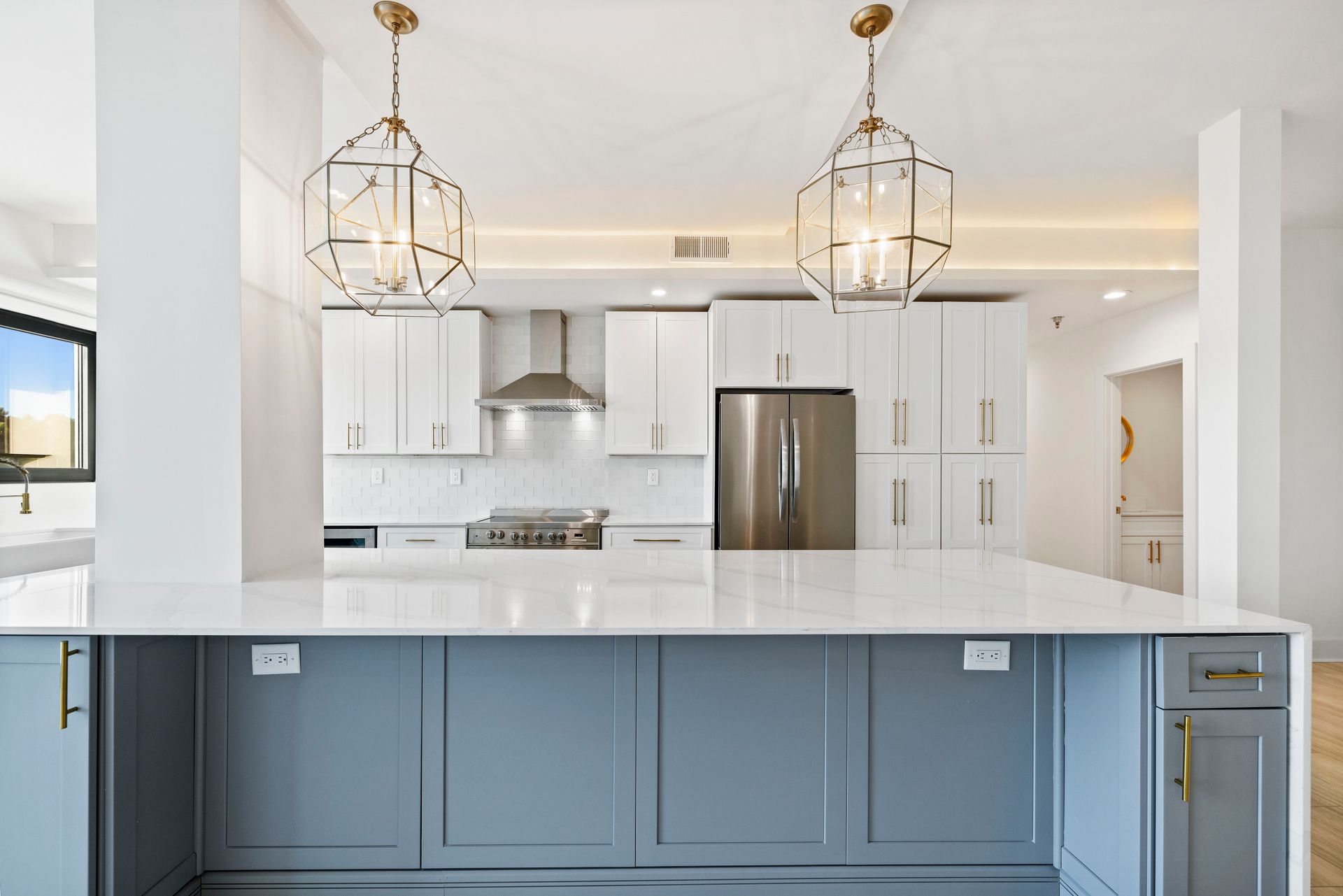 Modern kitchen with white and gray cabinets, large island, and pendant lights.